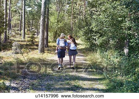 Parents giving daughters piggy back through forest View Large Photo Image Stock Photograph - Parents giving daughters piggy back through forest. Fotosearch