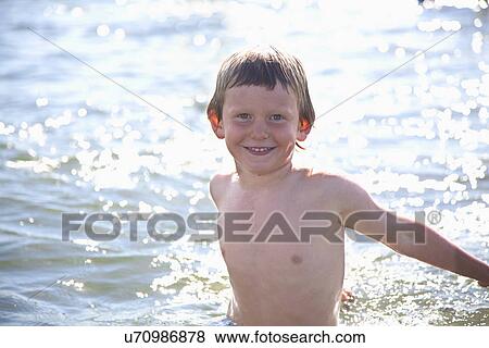 Stock Photo - Portrait of boy in water, Wales, UK. Fotosearch
