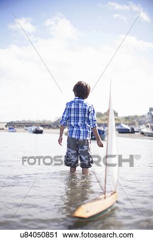 Portrait of boy playing with model boat View Large Photo Image Stock Image - Portrait of boy playing with model boat. Fotosearch