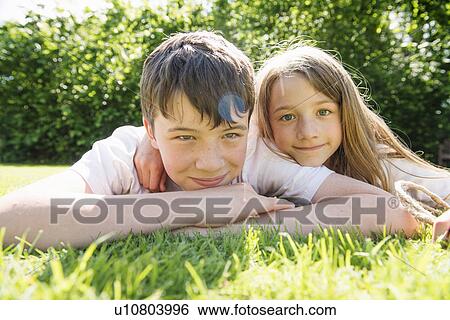 Stock Photograph - Portrait of brother and sister lying on grass. Fotosearch