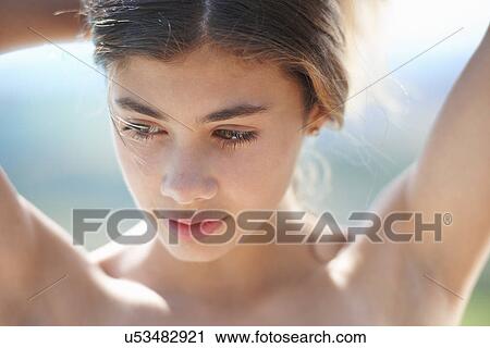 Portrait of brunette teenage girl looking down with arms raised View Large Photo Image Stock Image - Portrait of brunette teenage girl looking down with arms raised. Fotosearch
