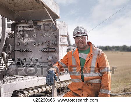 Stock Photograph - Portrait of drilling rig worker in hard hat and workwear. Fotosearch