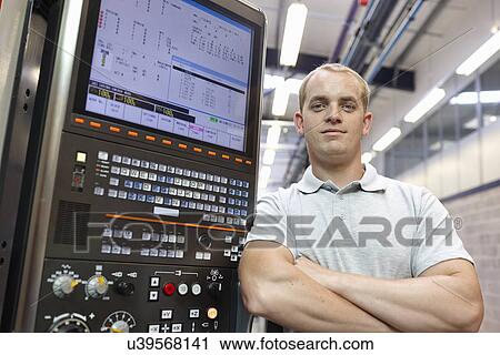Stock Image - Portrait of engineer and control panel in engineering factory. Fotosearch