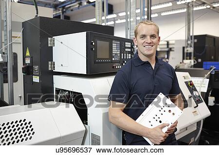 Stock Photo - Portrait of engineer holding component in engineering factory. Fotosearch