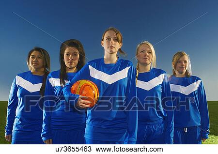Stock Image - Portrait of female football team, young woman holding ball. Fotosearch