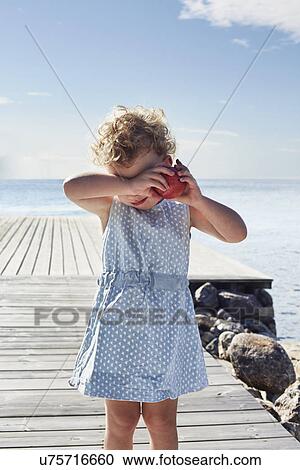 Stock Image - Portrait of female toddler with red apple, Utvalnas, Gavle, Sweden. Fotosearch