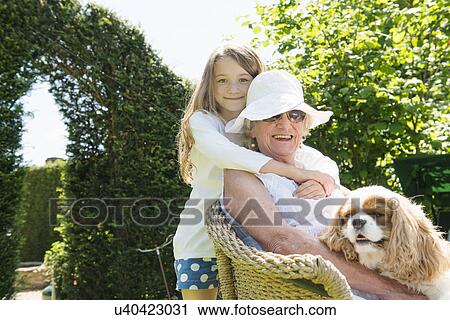 Stock Image - Portrait of grandmother and granddaughter with dog. Fotosearch