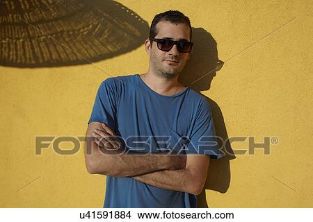 Portrait of man by yellow wall wearing sunglasses View Large Photo Image Picture - Portrait of man by yellow wall wearing sunglasses. Fotosearch