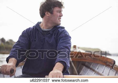 Stock Photo - Portrait of man rowing in boat, Wales, UK. Fotosearch