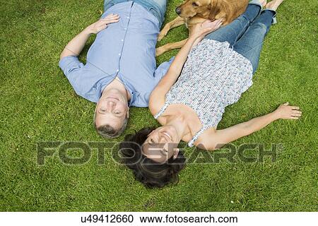 Portrait of mature couple lying on grass with dog View Large Photo Image Stock Image - Portrait of mature couple lying on grass with dog. Fotosearch