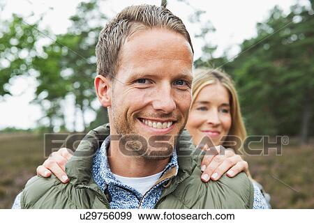 Portrait of mid adult man looking at camera, woman's hands on shoulders View Large Photo Image Stock Photo - Portrait of mid adult man looking at camera, woman's hands on shoulders. Fotosearch
