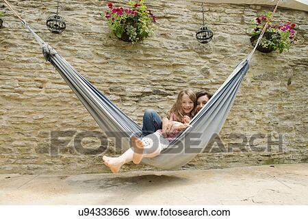 Stock Photograph - Portrait of mother and daughter in hammock. Fotosearch