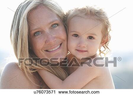 Stock Image - Portrait of mother hugging young daughter. Fotosearch