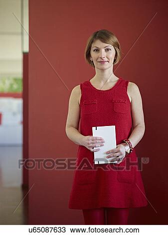 Stock Image - Portrait of office worker wearing red dress. Fotosearch