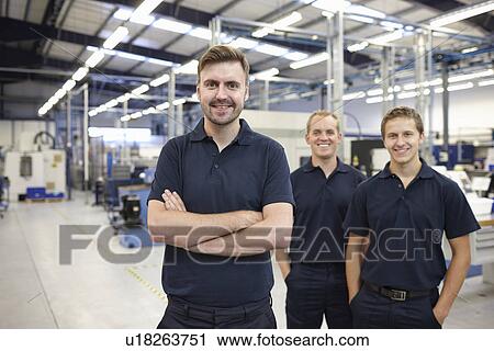 Stock Image - Portrait of three workers in engineering factory. Fotosearch