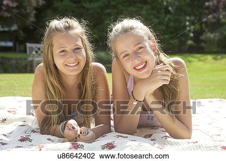 Stock Image - Portrait of two teenage girls lying on picnic blanket. Fotosearch
