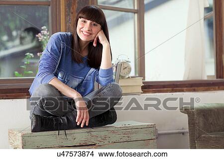 Picture - Portrait of woman sitting cross legged with hand on chin. Fotosearch