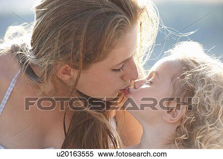 Stock Photography - Portrait of young girl kissing older sister. Fotosearch