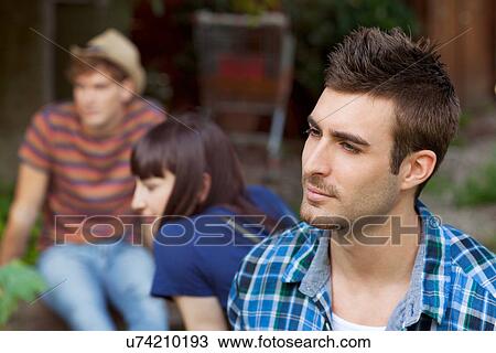 Stock Image - Portrait of young man with friends in background. Fotosearch