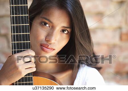 Stock Image - Portrait of young woman holding guitar. Fotosearch