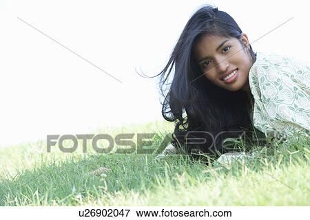 Portrait of young woman lying on grass View Large Photo Image Stock Photo - Portrait of young woman lying on grass. Fotosearch