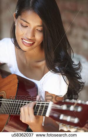 Portrait of young woman playing guitar View Large Photo Image Stock Photo - Portrait of young woman playing guitar. Fotosearch