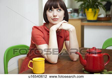 Portrait of young woman sitting at kitchen table View Large Photo Image Stock Image - Portrait of young woman sitting at kitchen table. Fotosearch