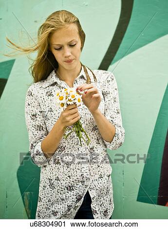 Stock Image - Portrait of young woman with bunch of daisies. Fotosearch