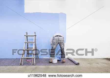 Rear view of man painting wall blue View Large Photo Image Stock Photo - Rear view of man painting wall blue. Fotosearch