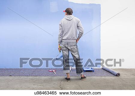 Rear view of man painting wall blue View Large Photo Image Stock Photography - Rear view of man painting wall blue. Fotosearch