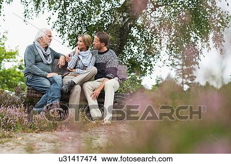 Picture - Senior man and mid adult couple sitting on log. Fotosearch