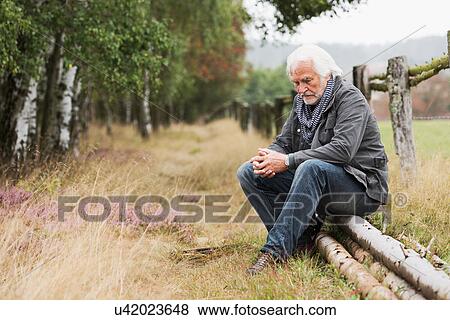 Stock Photo - Senior man sitting on log. Fotosearch