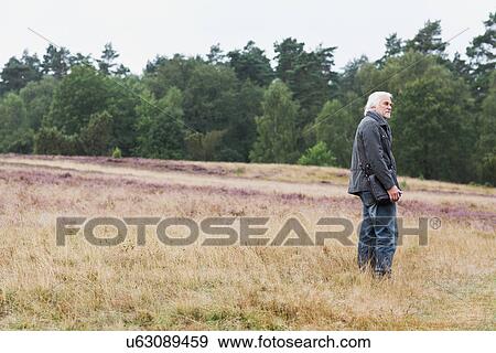 Senior man standing in meadow View Large Photo Image Stock Photo - Senior man standing in meadow. Fotosearch