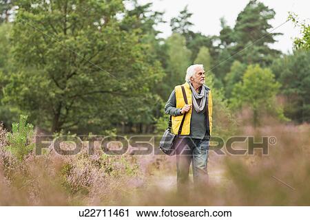 Stock Image - Senior man walking in meadow. Fotosearch
