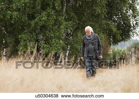 Senior man walking in meadow View Large Photo Image Stock Photo - Senior man walking in meadow. Fotosearch