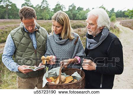 Stock Image - Senior man with mid adult couple and basket of mushrooms. Fotosearch