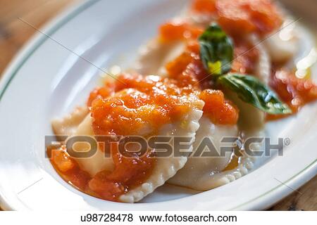 Stock Photo - Still life with ravioli, tomato sauce and basil garnish. Fotosearch