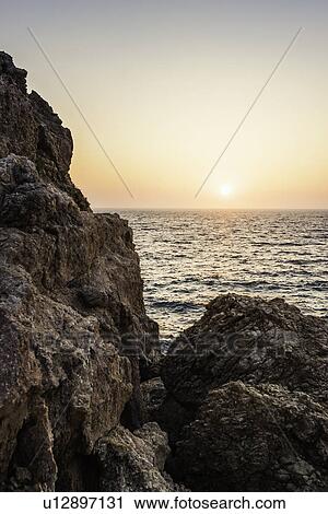 Stock Image - Sunset over rocks at Seitani Bay, Samos, Greece. Fotosearch