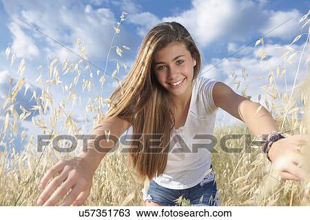 Stock Image - Teenage girl in field parting crops, Tuscany, Italy. Fotosearch