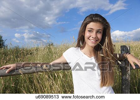 Stock Image - Teenage girl leaning on wooden fence, Tuscany, Italy. Fotosearch