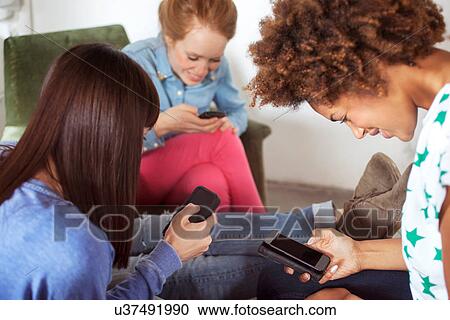 Three female friends using smartphones View Large Photo Image Stock Image - Three female friends using smartphones. Fotosearch