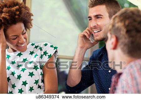 Three friends laughing, man on smartphone View Large Photo Image Picture - Three friends laughing, man on smartphone. Fotosearch