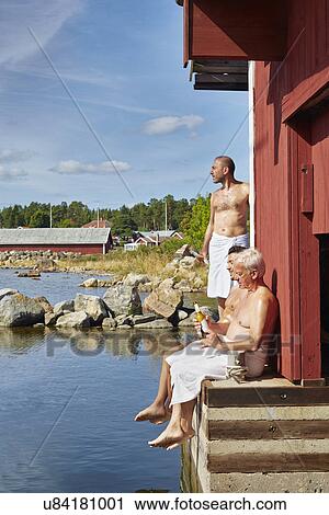 Stock Image - Three male friends outside sauna. Fotosearch