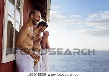 Three male friends standing outside sauna enjoying beer View Large Photo Image Stock Photo - Three male friends standing outside sauna enjoying beer. Fotosearch