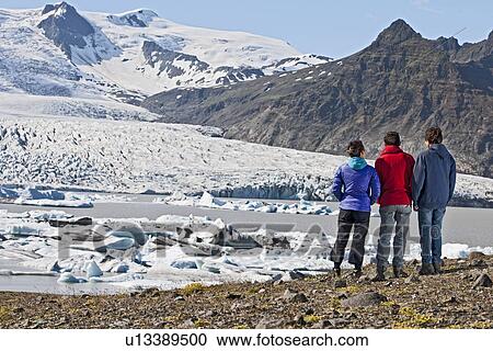 Stock Image - Three people admiring Fjallsarlon lagoon, Skaftafell, Iceland. Fotosearch
