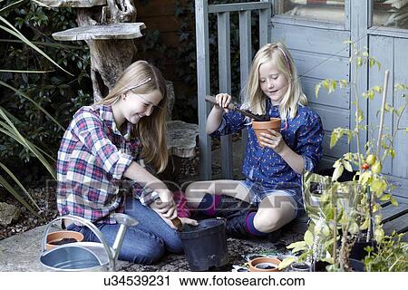 Two girls in garden planting seeds into pots View Large Photo Image Stock Image - Two girls in garden planting seeds into pots. Fotosearch