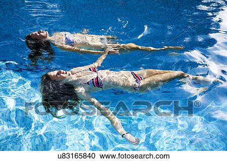 Two teenage girls floating in swimming pool View Large Photo Image Stock Image - Two teenage girls floating in swimming pool. Fotosearch