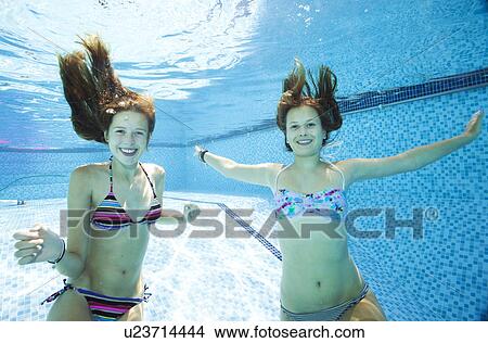 Picture - Two teenage girls swimming underwater in swimming pool. Fotosearch