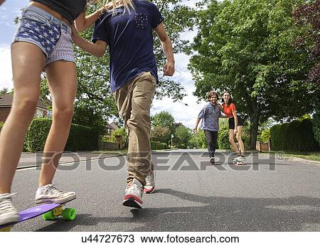 Stock Image - Two young couples skateboarding on street. Fotosearch