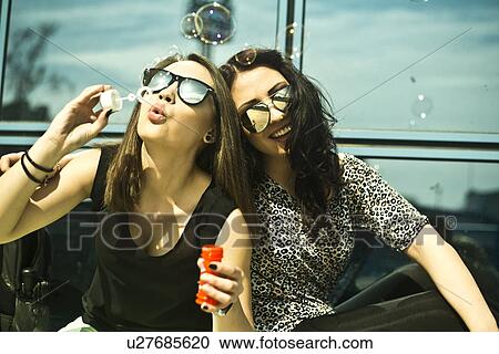 Stock Image - Two young woman blowing bubbles. Fotosearch